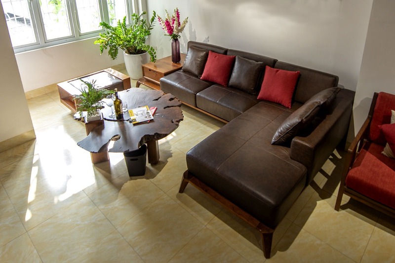 Không gian nội thất phòng khách của chủ nhà mệnh Thổ với điểm nhấn là bộ bàn ghế sofa màu nâu trầm kết hợp với những chiếc gối màu đỏ tương sinh ấn tượng